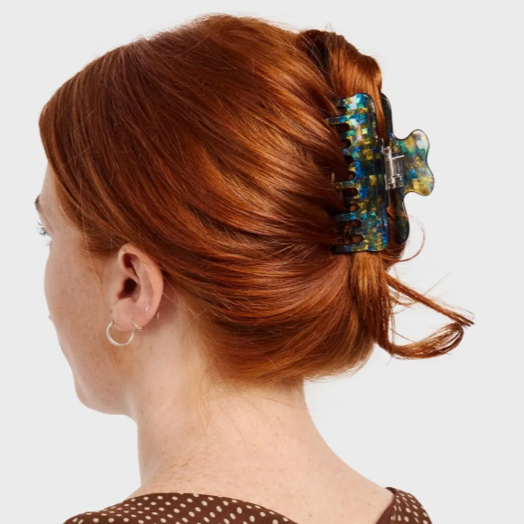 Woman with red hair tied back with a decorative hair clip on a white background