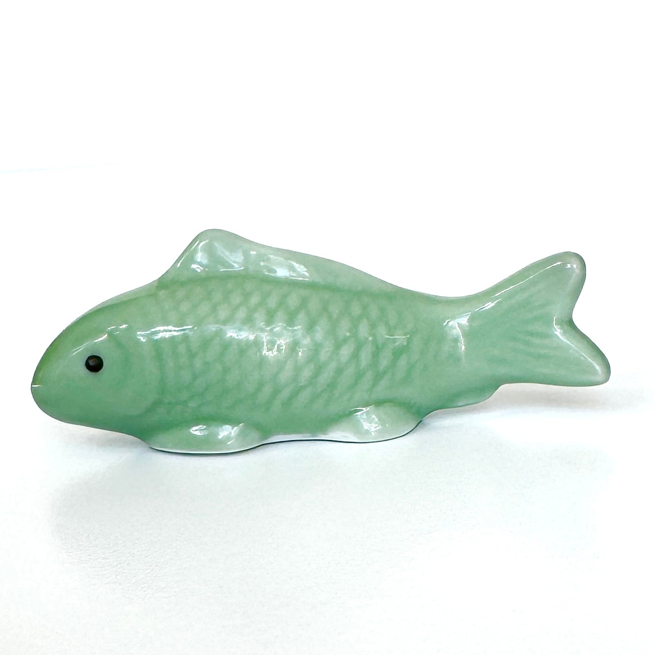 Green ceramic fish-shaped object on a white background